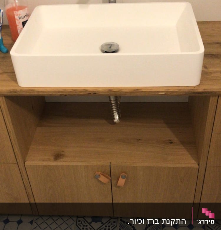כיור עם ברז וצינור מתכת מתחת